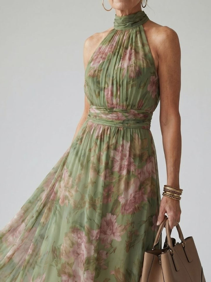 Woman posing in a flowing striped maxi dress against a plain backdrop