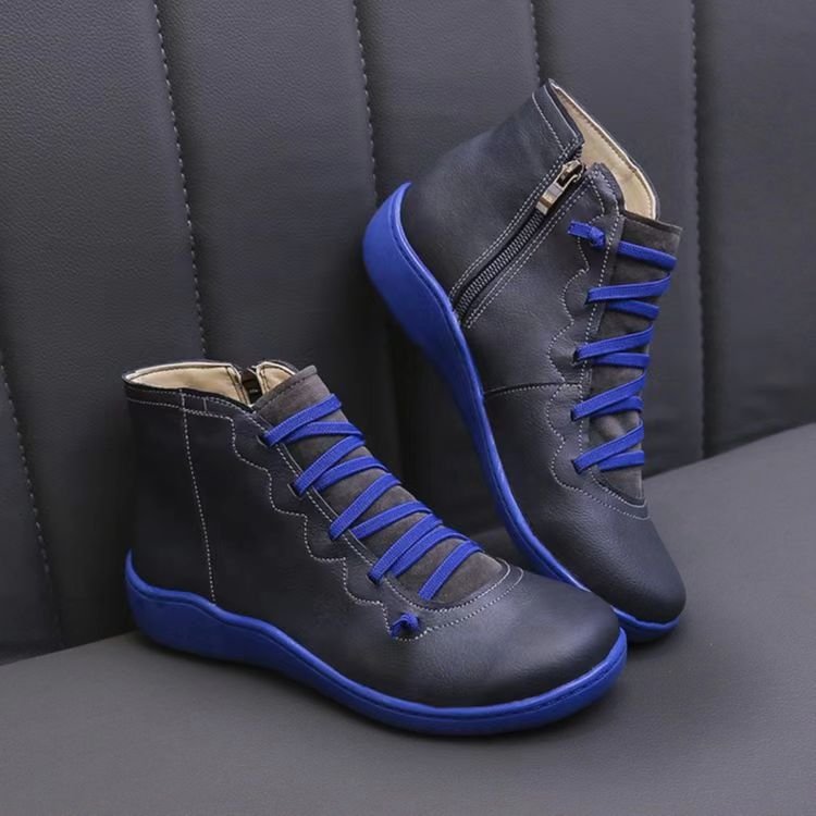 Pair of black high-top sneakers with blue laces on a gray background