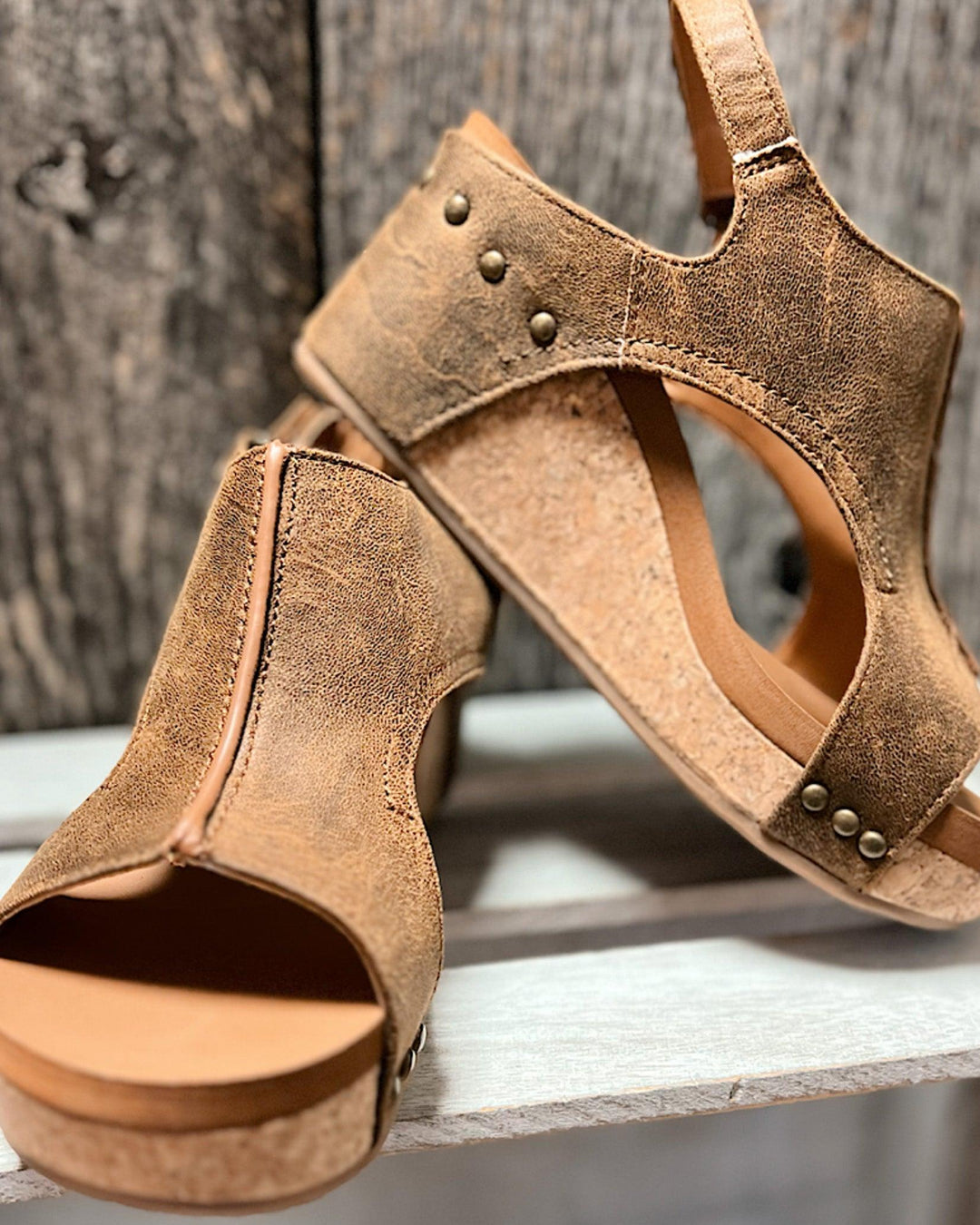 Angled front view foot wearing sandals on gray floor surface