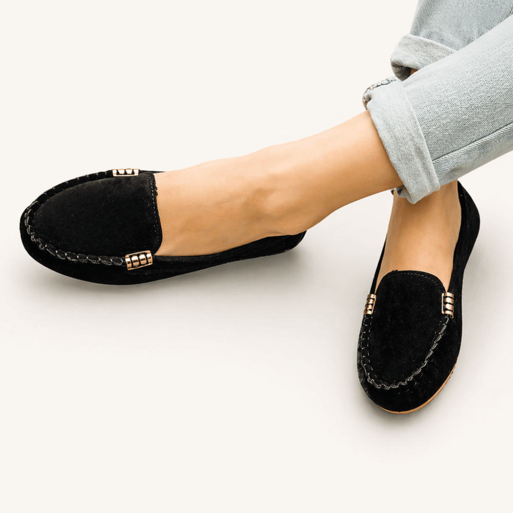  Woman showcasing classic loafers with a casual outfit on a plain background.