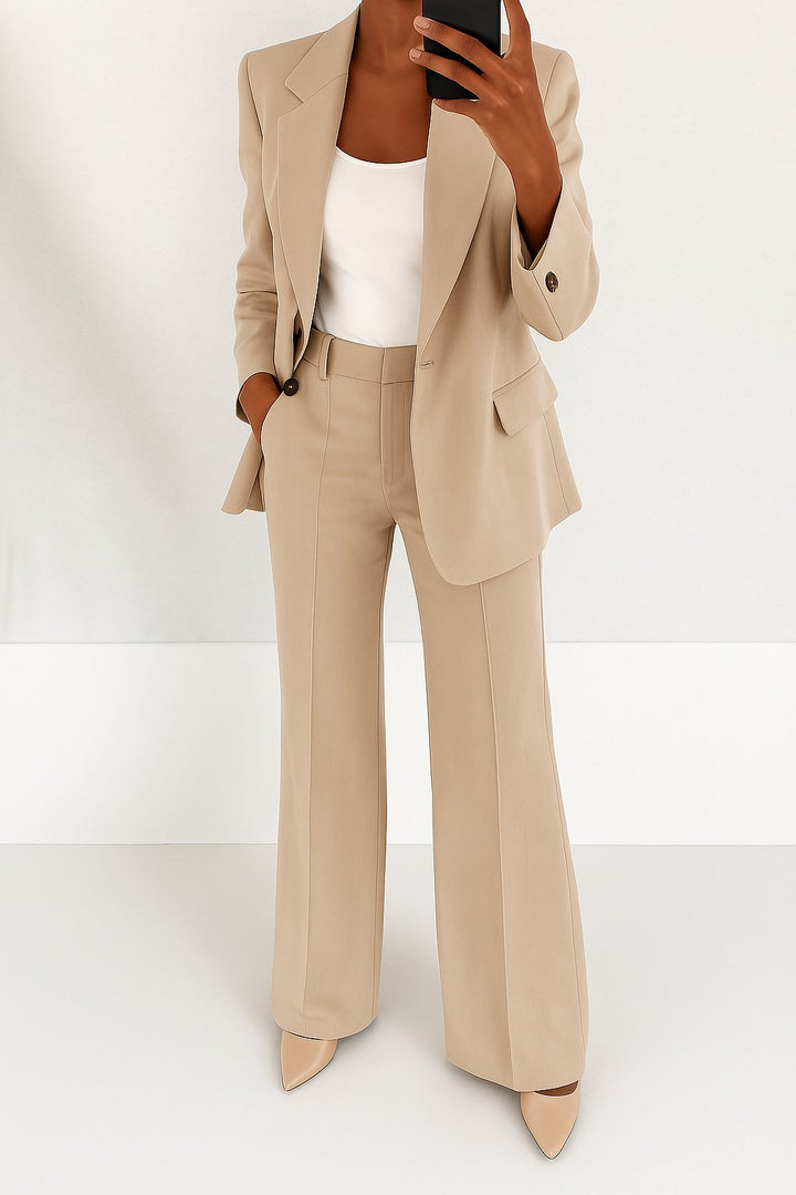 Woman in a modern two-piece blazer outfit standing on a plain background.