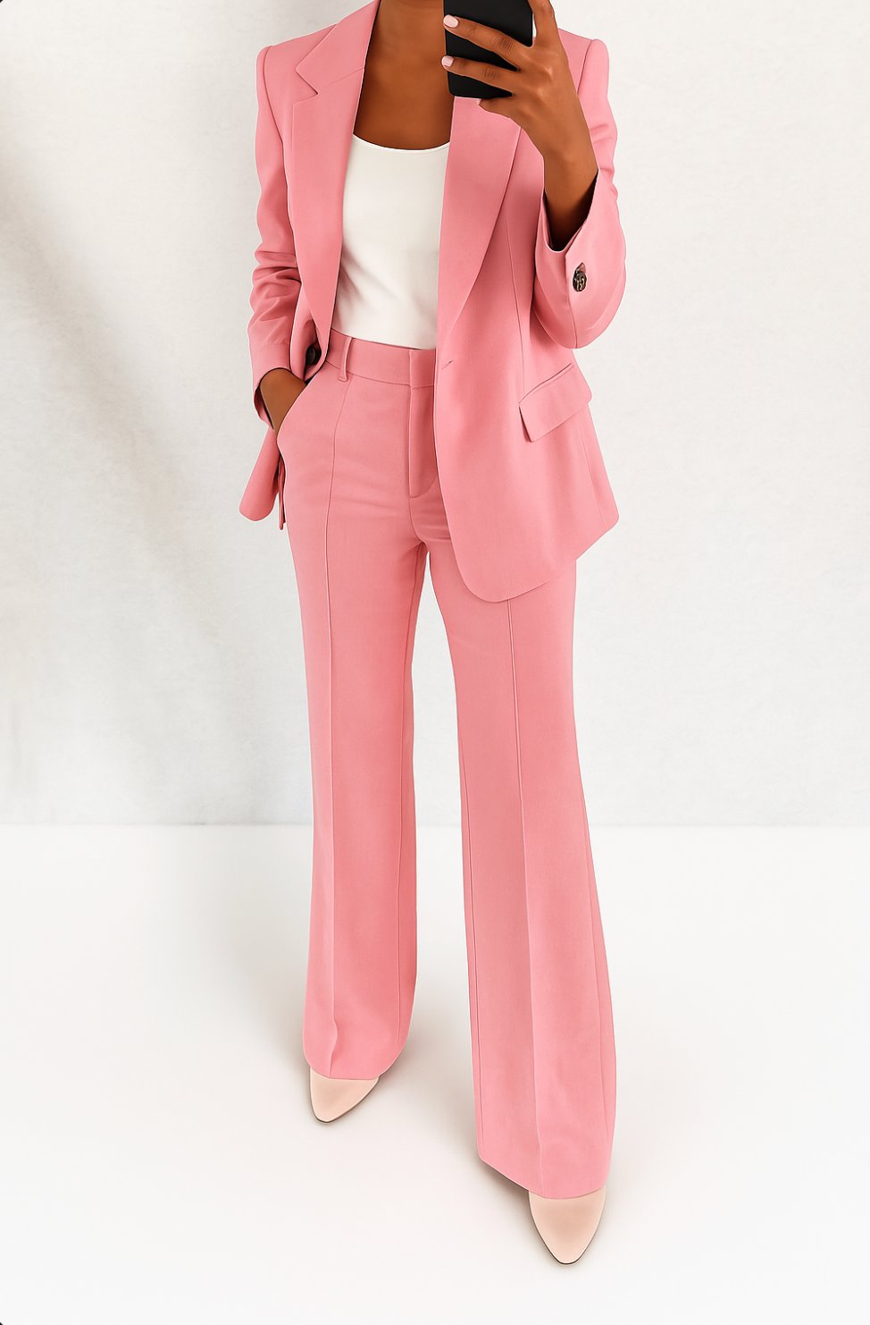 Model wearing a minimalist blazer set with matching trousers on a plain background.