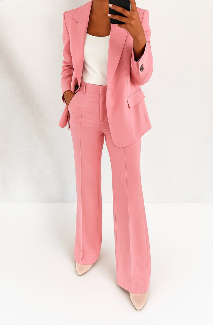 Model wearing a minimalist blazer set with matching trousers on a plain background.