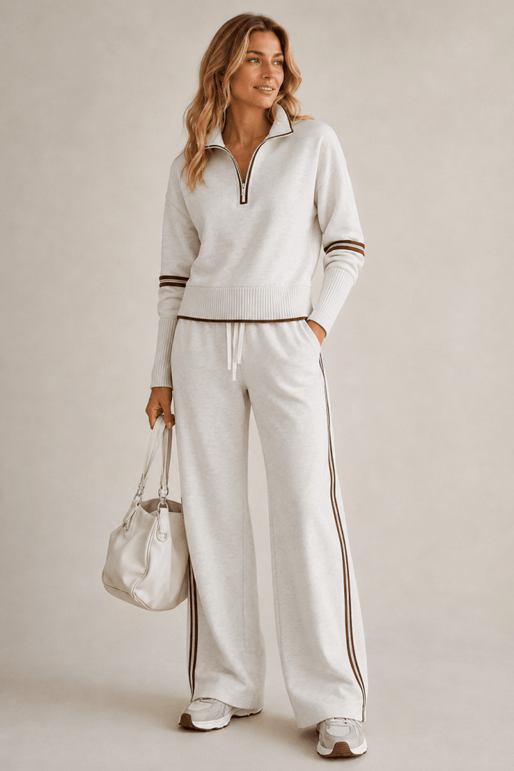Female model wearing a two-piece outfit with stripe details on a plain background.