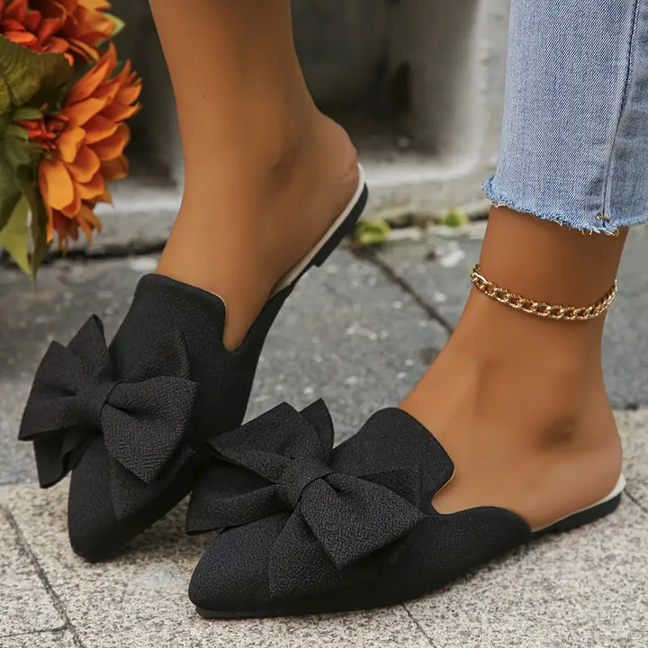 Close-up of pointed toe flats with bow detail visible