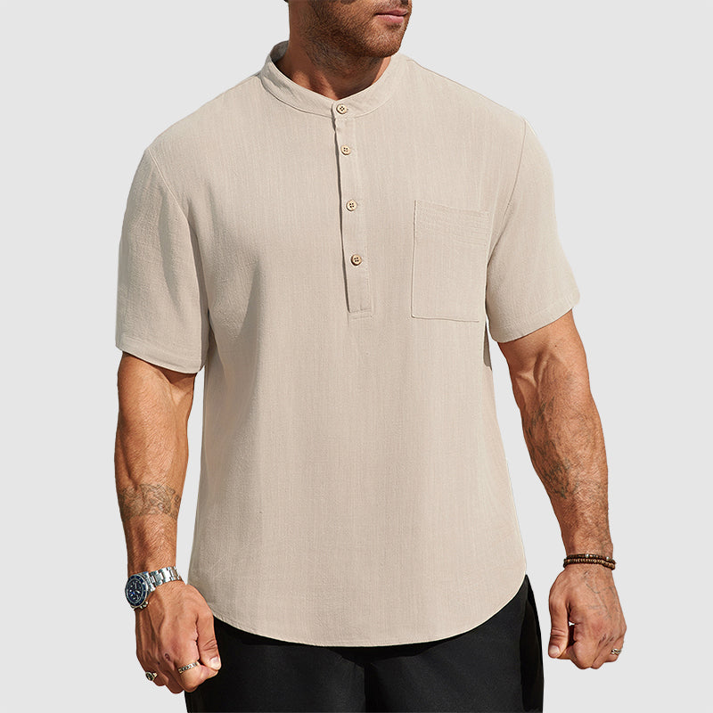  Man wearing an open collar shirt with chest pocket against a plain background.