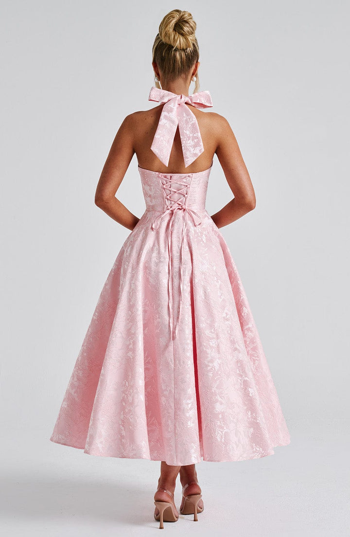 Female model showcasing a sleeveless halter midi dress with a flowing silhouette.
