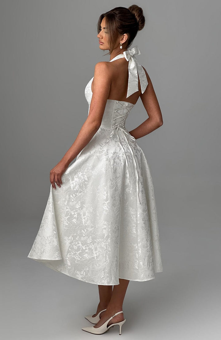 Female model in a midi-length halter dress photographed against a plain backdrop.