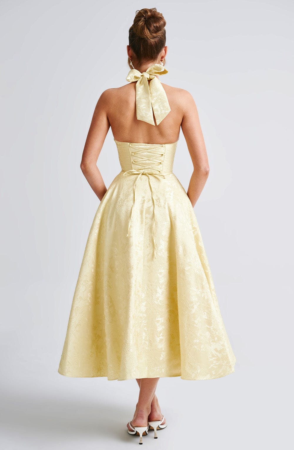 Female model showcasing a graceful halter dress with a midi-length silhouette.

