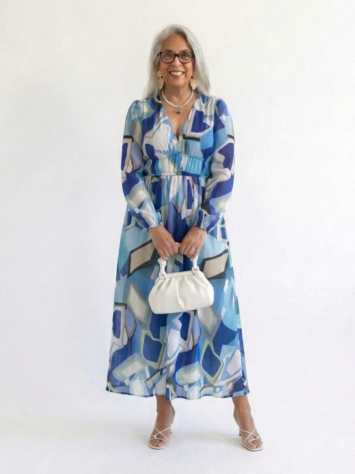 Female model in a green floral maxi dress with soft movement against a plain background.