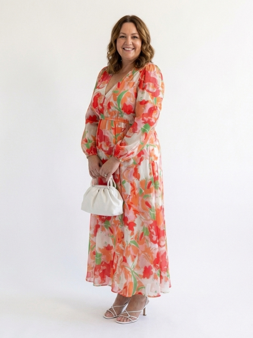 Female model in a flowing green floral long sleeve maxi dress on a plain background.
