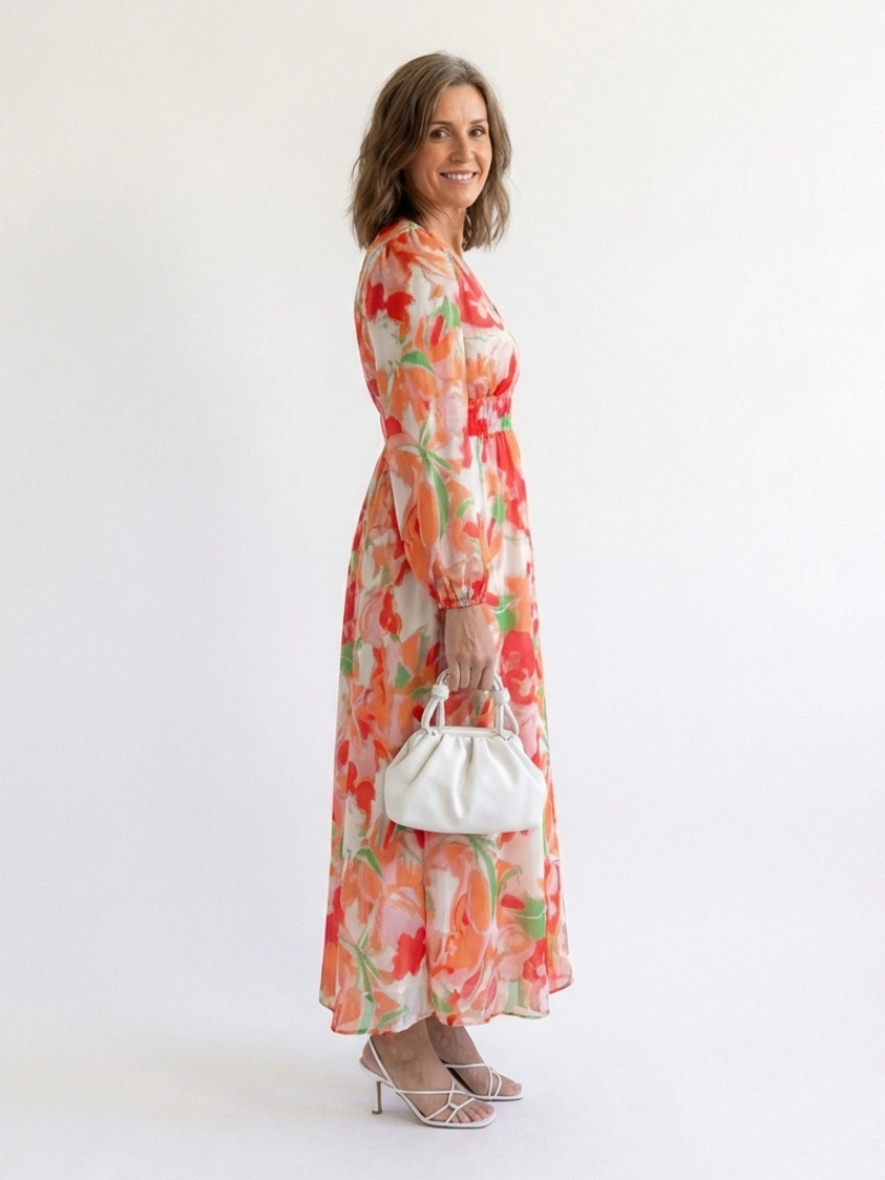 Woman styled in a v neck floral maxi dress with long sleeves against a plain background.