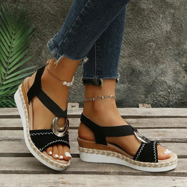 Front close-up of elegant sandal on foot over plain background.