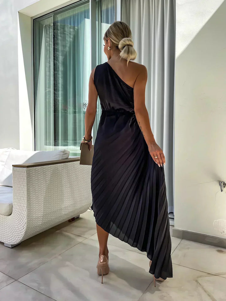 Woman model showcasing a one shoulder pleated midi dress designed for occasion wear on a plain background, back view