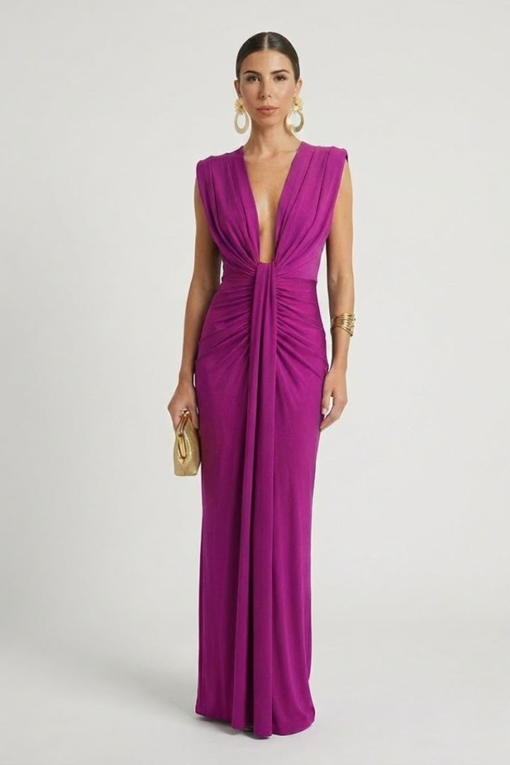 Woman in floor-length formal pink dress standing on plain gray background.