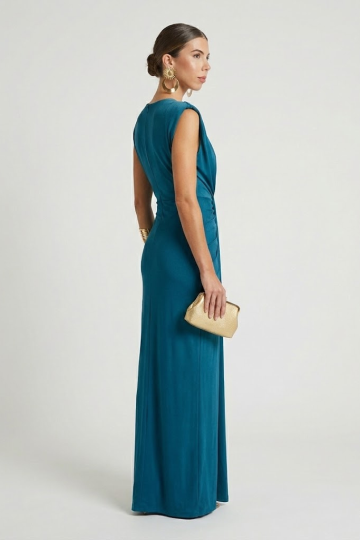 Woman showcasing full-length side sleeveless dress with deep neckline and pleats.
