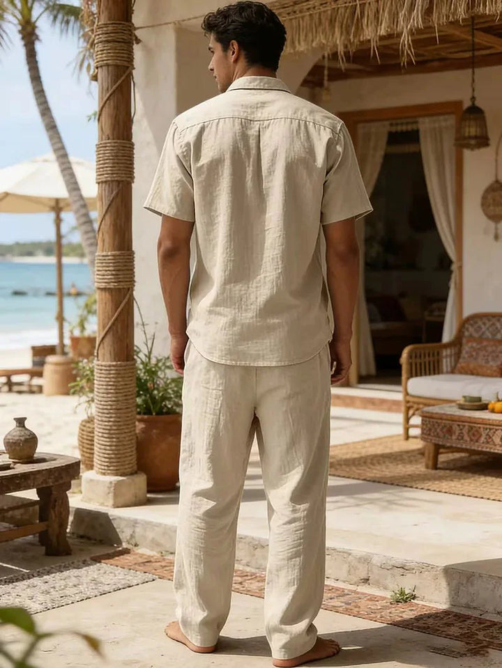  Male model wearing a warm-weather shirt and trouser set on a plain background.