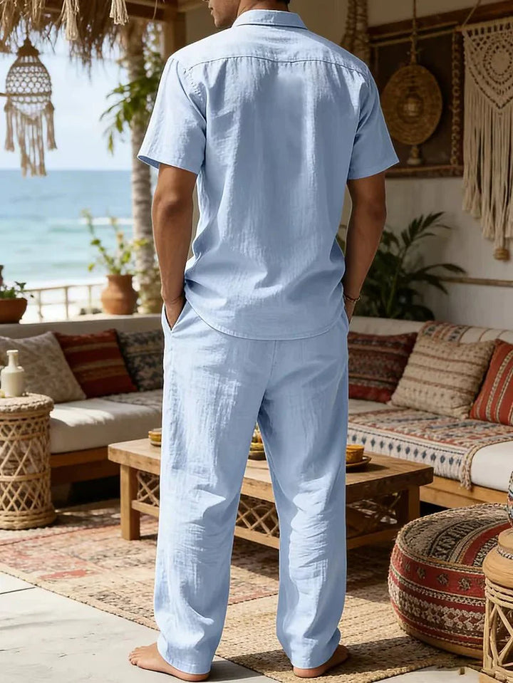  Man wearing a matching short-sleeve shirt and trousers on a plain background.