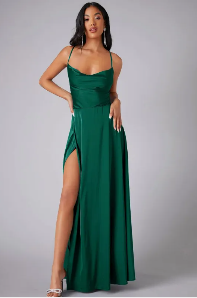 Female model in a draped cowl neck maxi dress with elegant movement on a plain background.