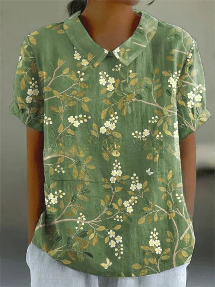 Woman wearing a feminine floral top on a plain background.