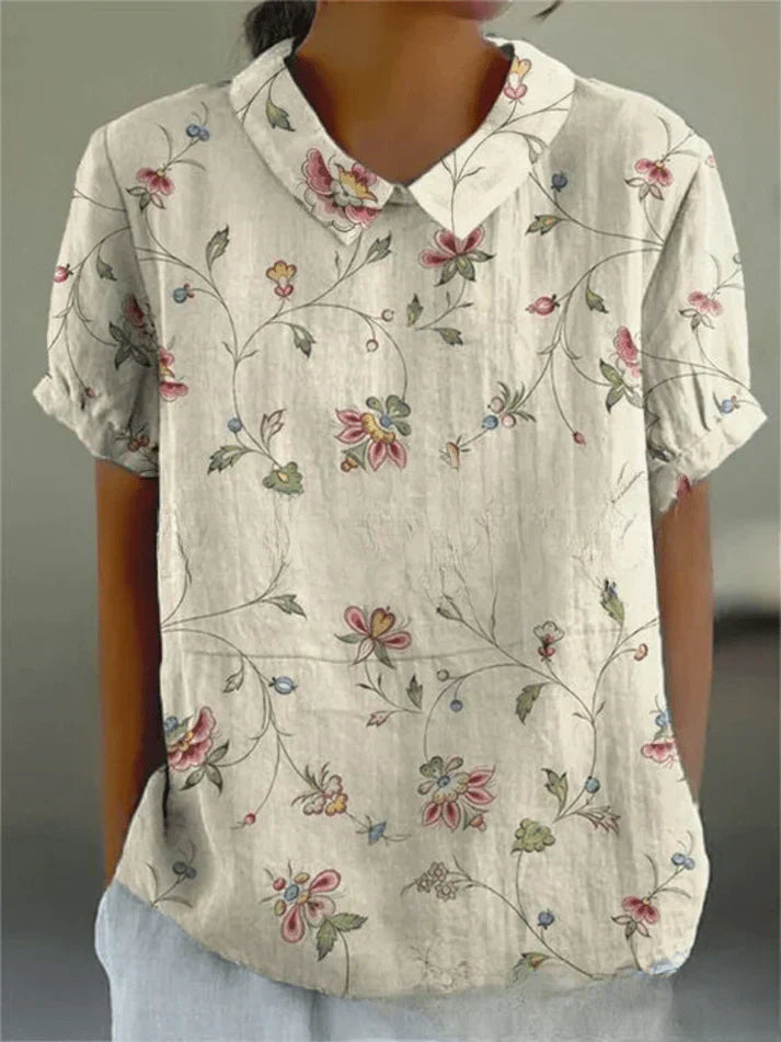 Female model wearing a floral print blouse on a clean background.