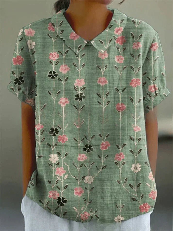 Woman wearing a floral blouse against a plain background.