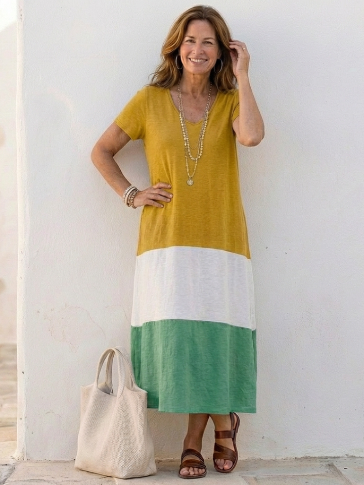Female standing in a short sleeve color block midi dress against a plain backdrop.