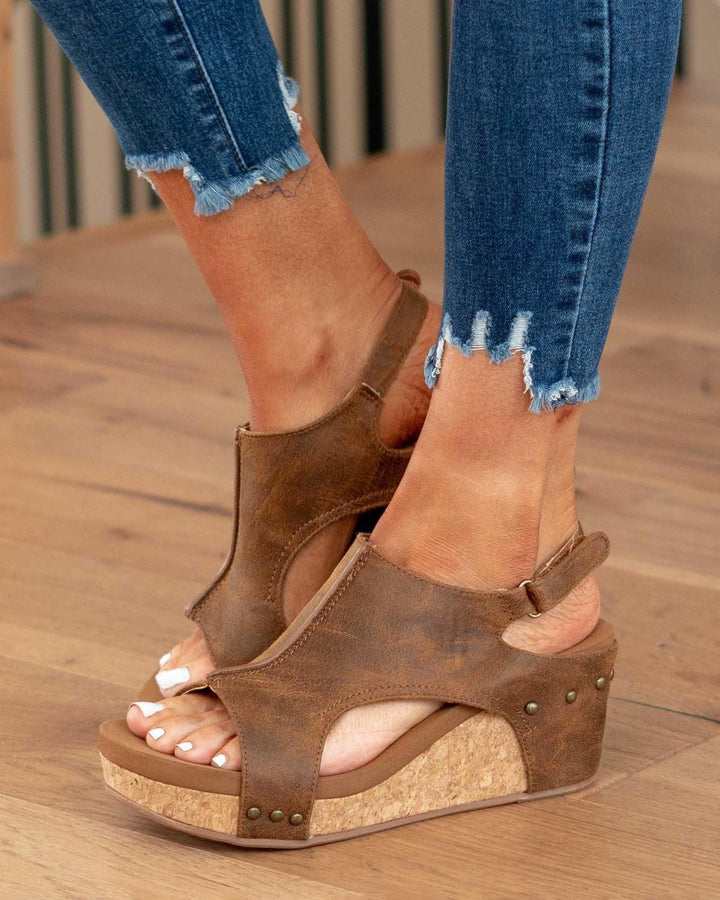 Foot model walking pose in hiking sandals on brown floor
