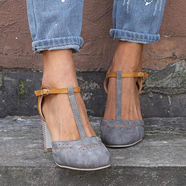 Elegant closed-toe sandals displayed on woman against plain wall background.