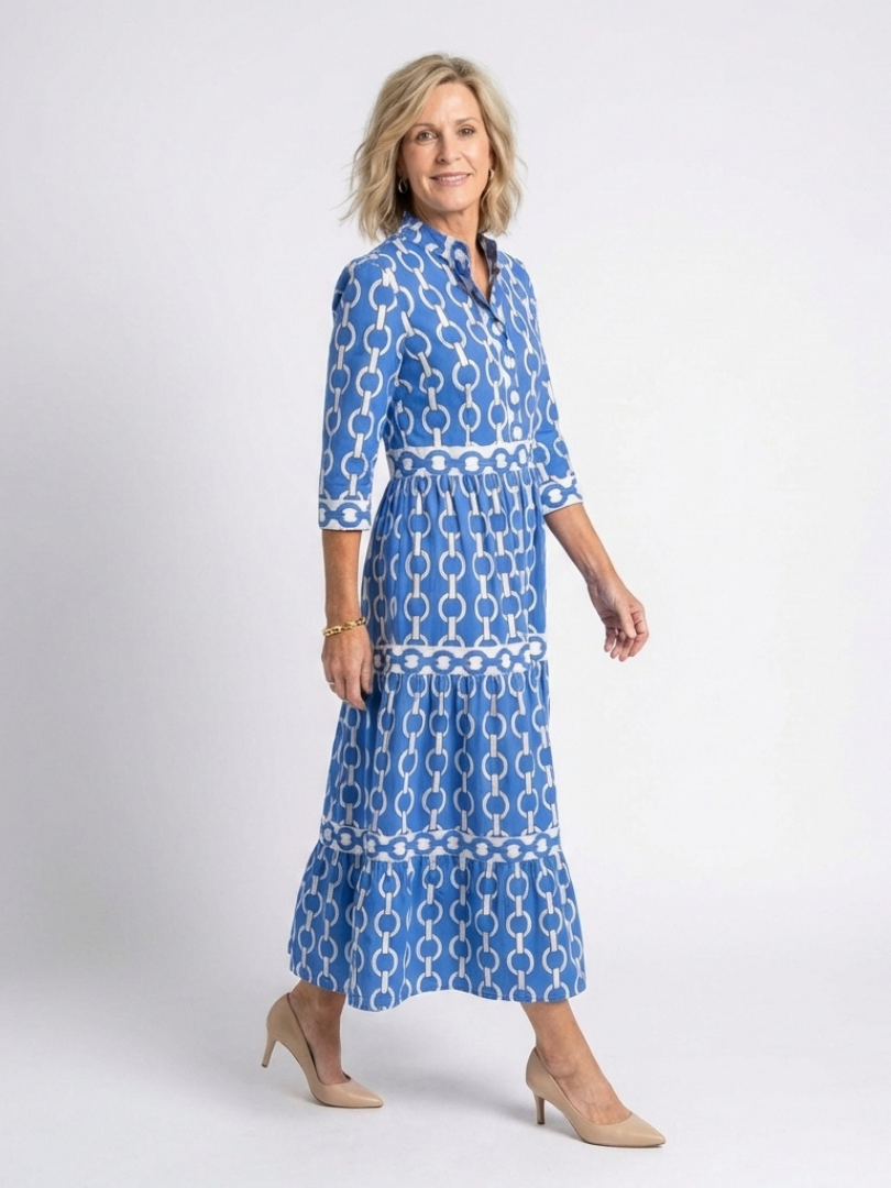 Female model posing in a geometric chain print midi dress on a plain backdrop.