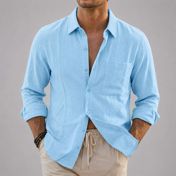 Female model wearing a relaxed button up shirt against a plain background.