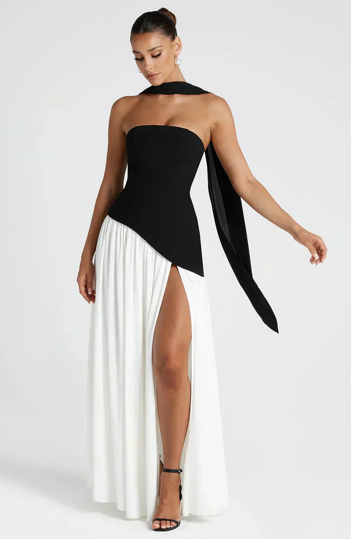 Female model showcasing a long asymmetric dress with an elegant drape.
