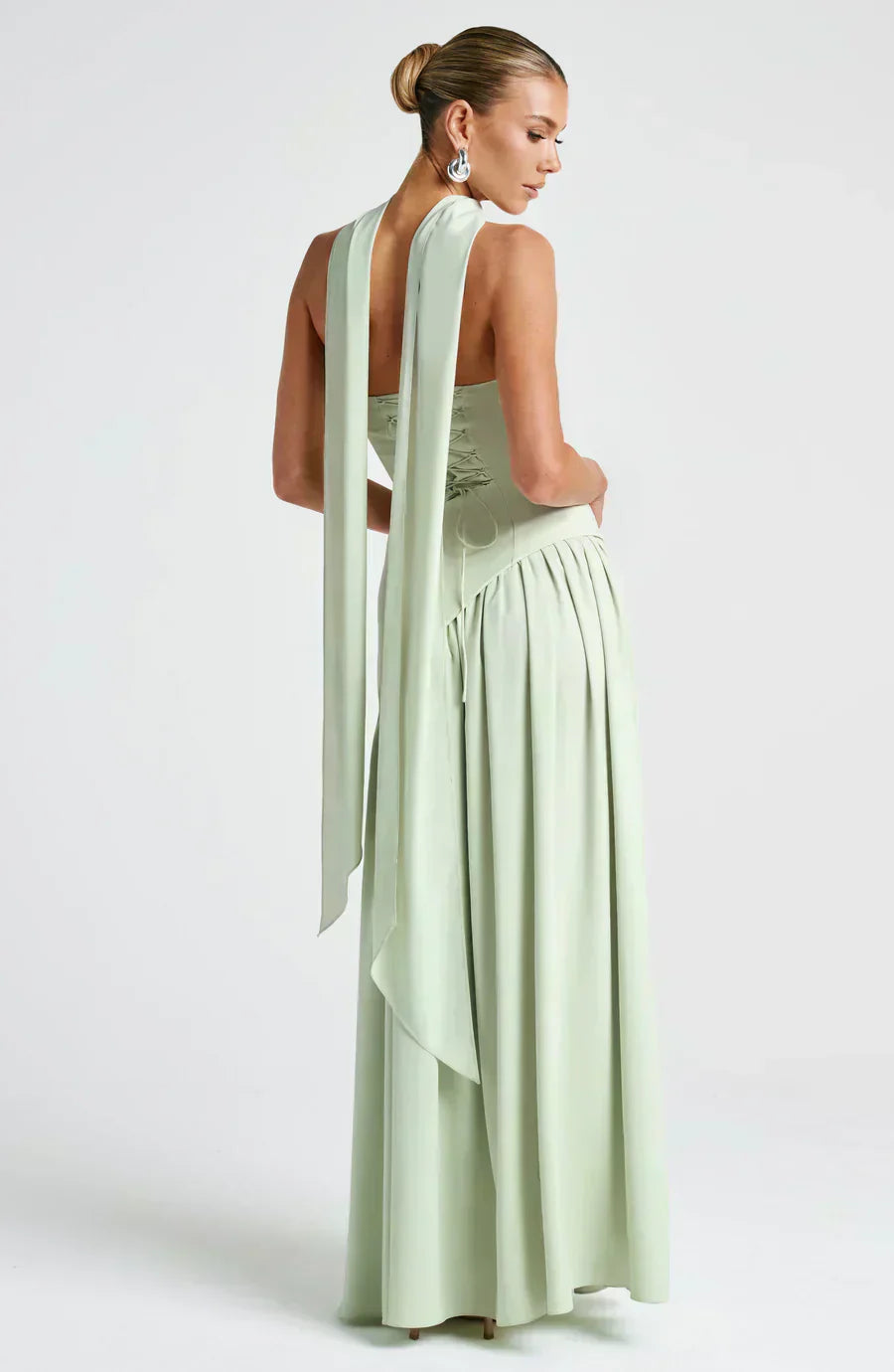 Woman in a modern maxi dress with a one-shoulder silhouette on a plain background.
