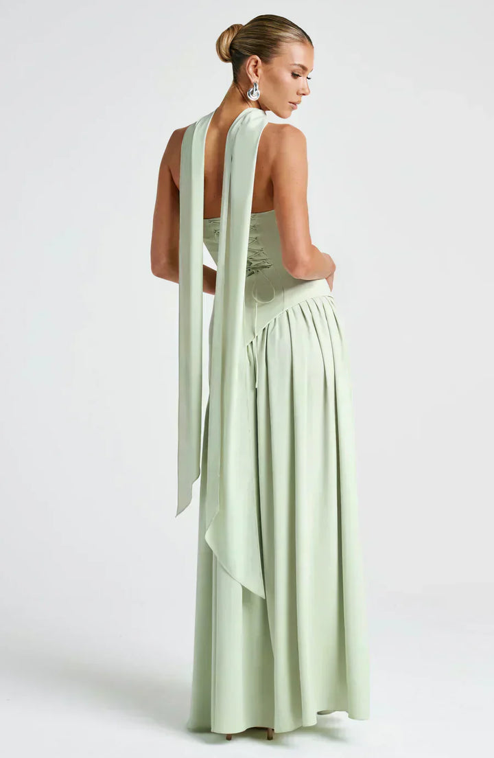 Woman in a modern maxi dress with a one-shoulder silhouette on a plain background.
