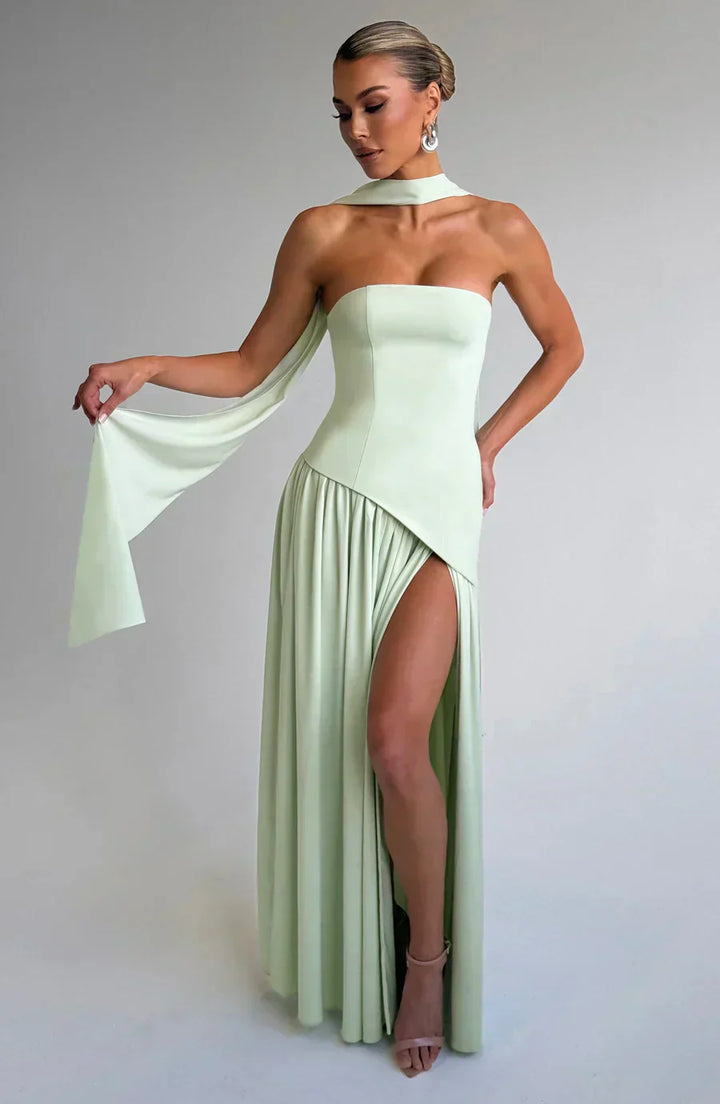 Model posing with polished dress shape on plain background.