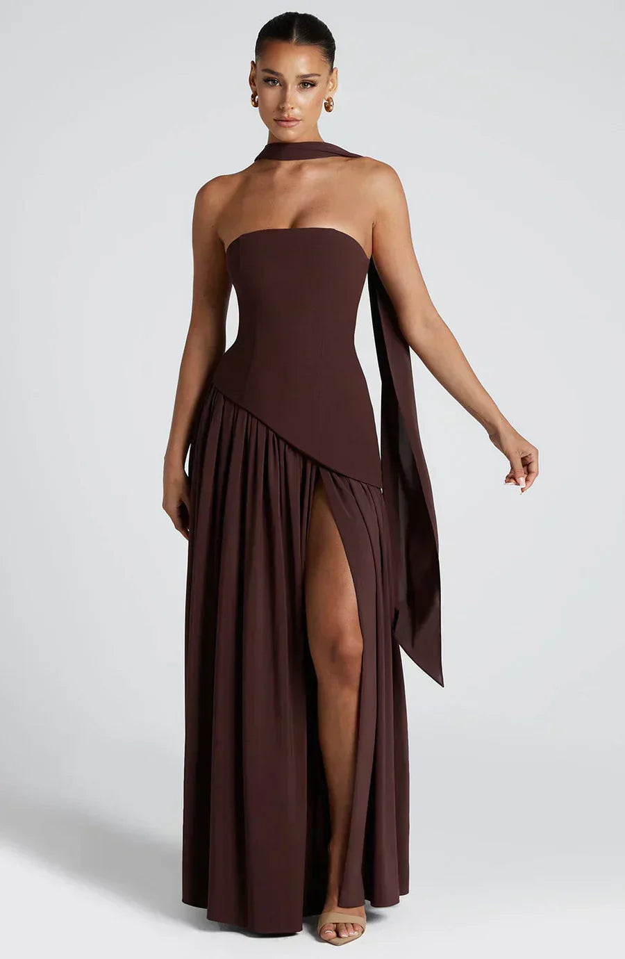 Model displaying elegant wedding guest look on plain background.
