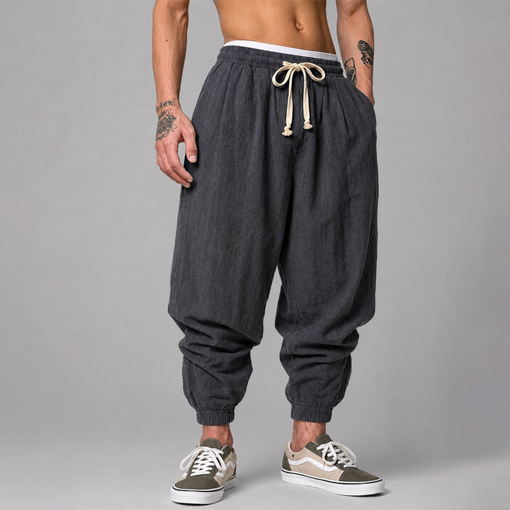 
Woman wearing relaxed jogger pants with cuffed hems on a plain background.