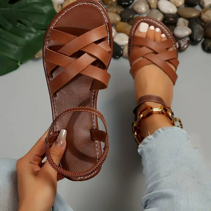 Top view of crossed strap sandals on plain studio background