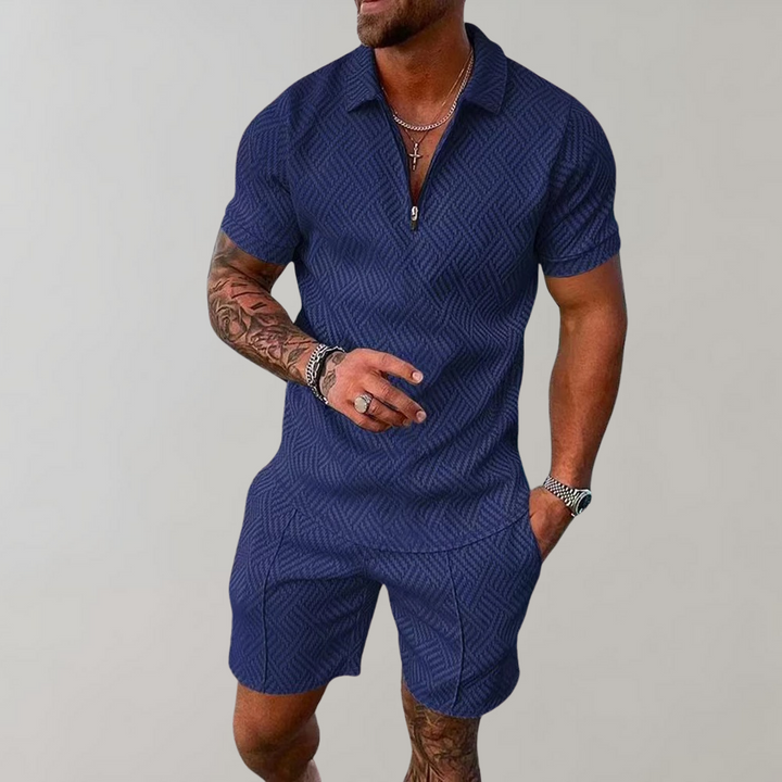  Man wearing a zip-neck short-sleeve shirt with coordinated shorts on a plain background.