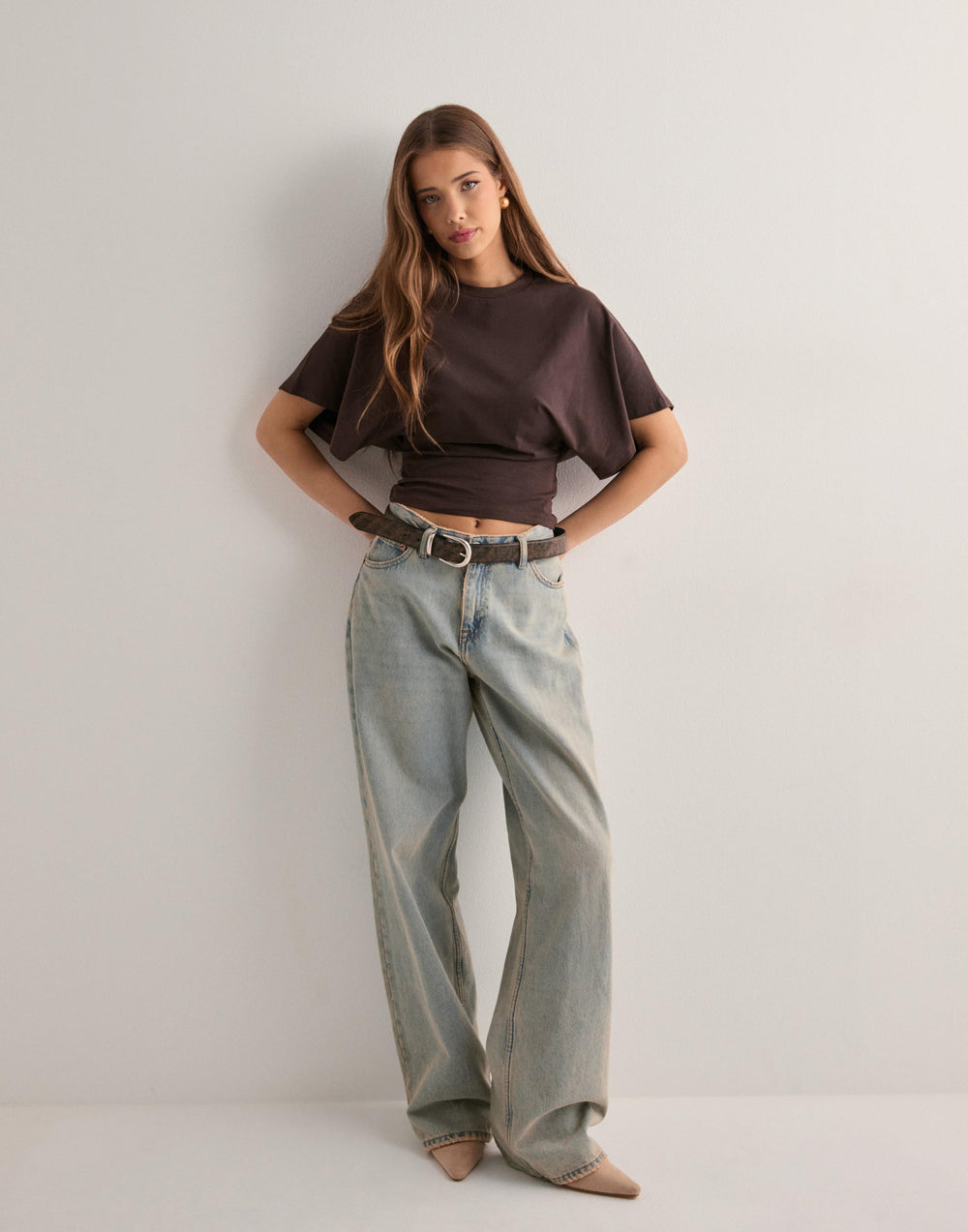 Woman posing front angle showcasing slim fit casual top plain background