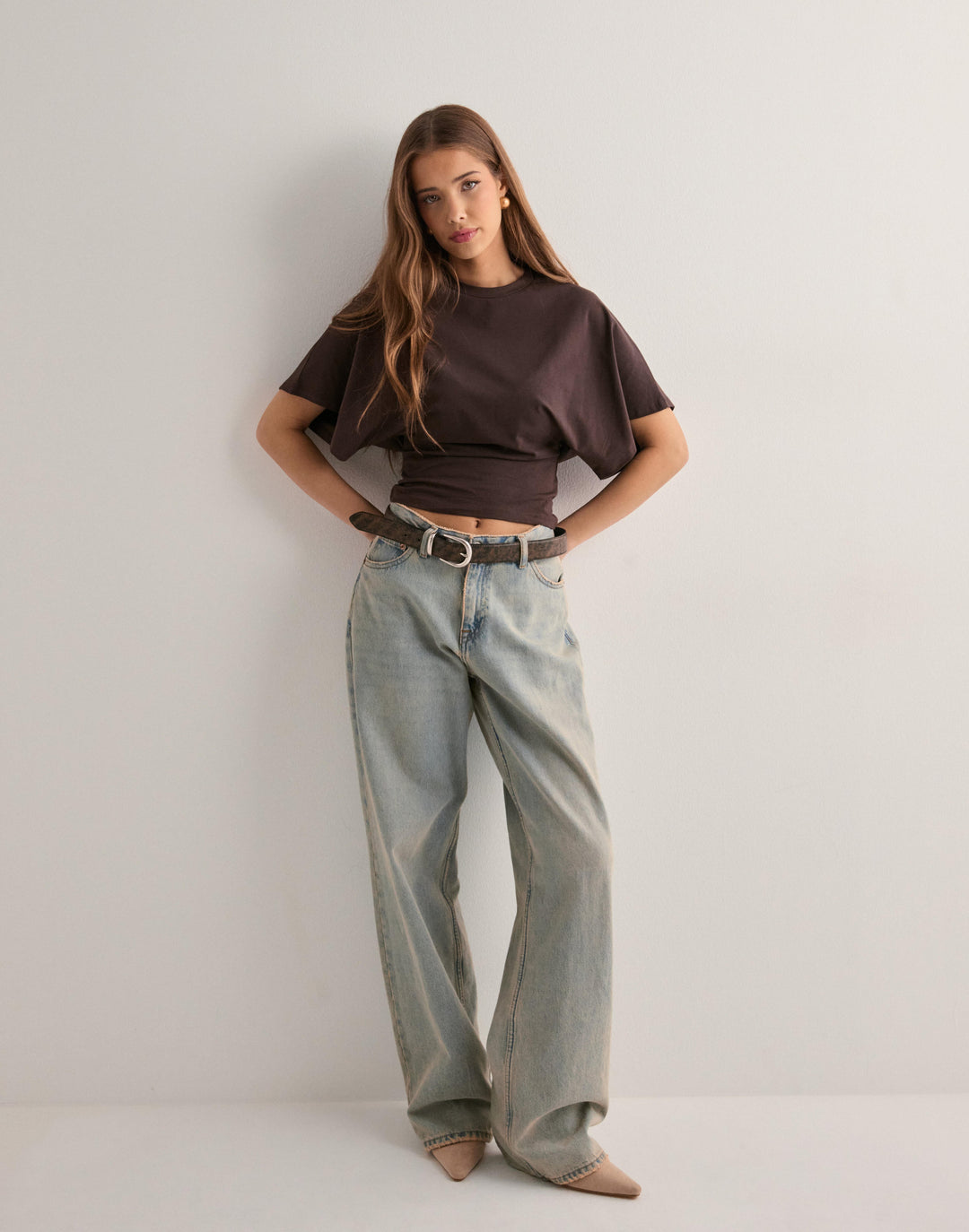 Woman posing front angle showcasing slim fit casual top plain background