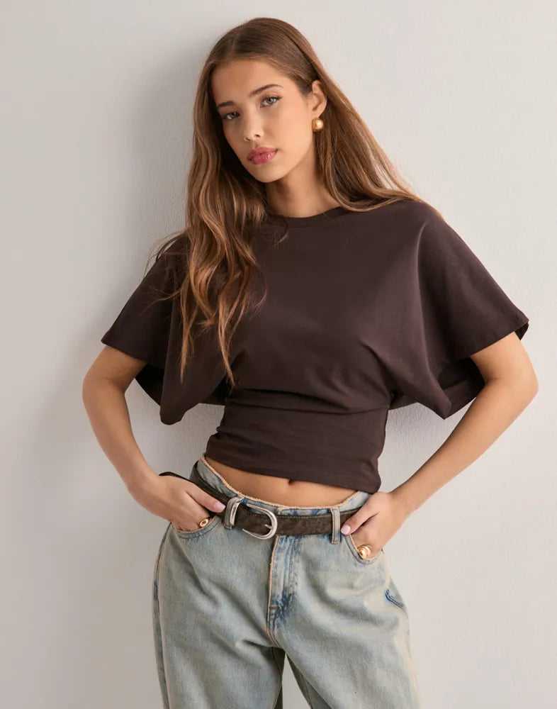Female model wearing fitted flared sleeve shirt front view plain background