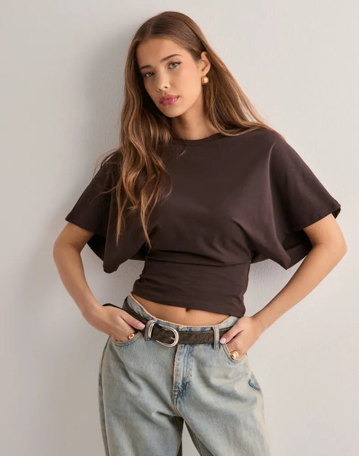 Female model wearing fitted flared sleeve shirt front view plain background