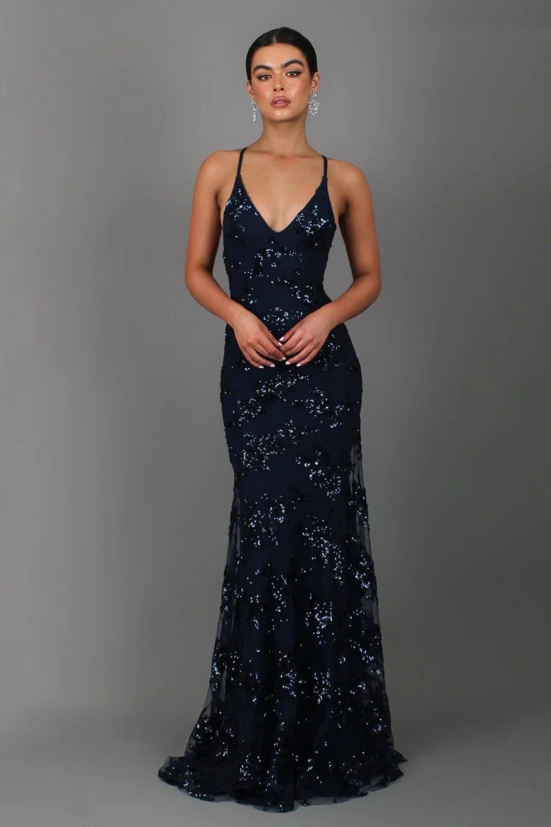 Female model wearing a shimmering evening gown with deep V neckline on a plain background.