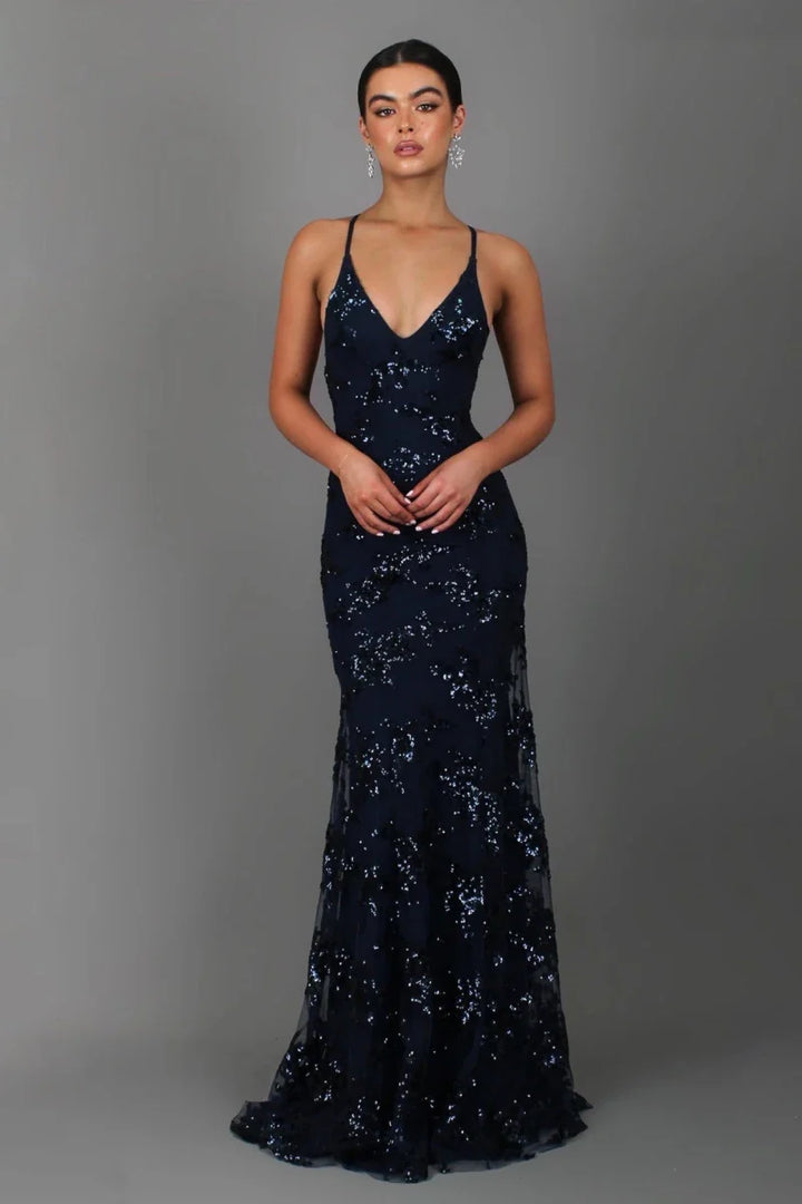 Female model wearing a shimmering evening gown with deep V neckline on a plain background.