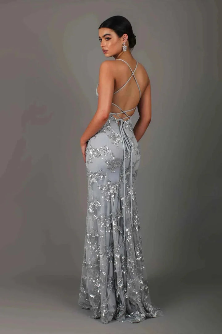 Model in a sparkling formal dress with slim silhouette on a plain background.