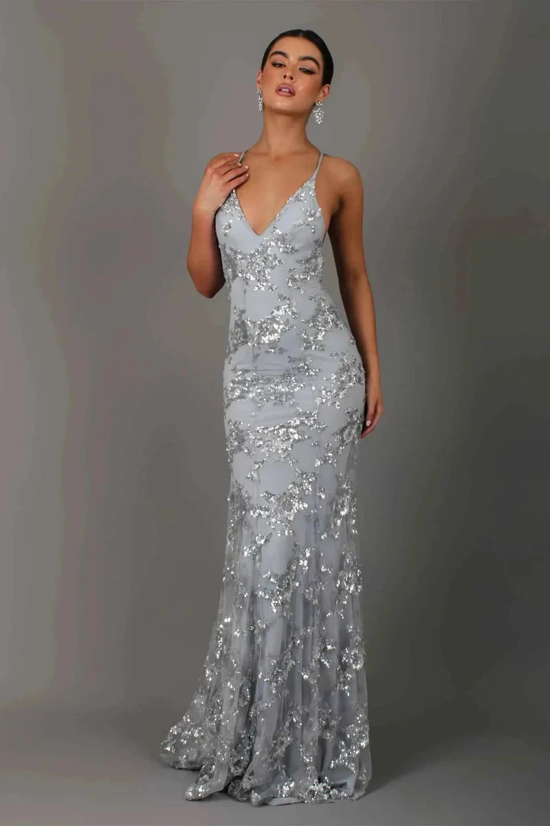  Model wearing a long sparkling formal gown with delicate straps on a plain background.