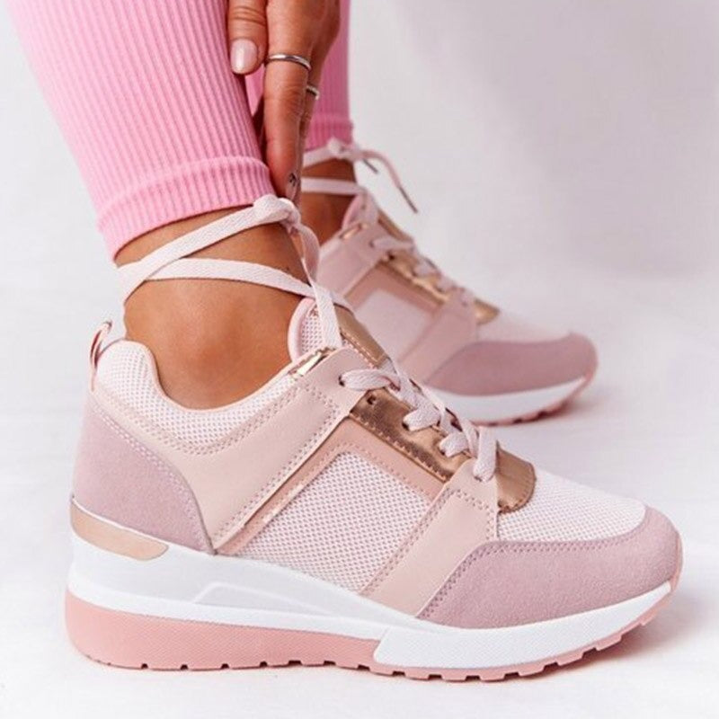 Pink and white sneakers worn with pink pants on a light background