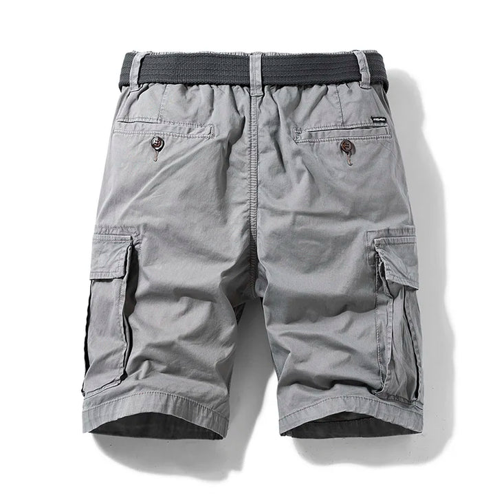  Model standing in casual cotton cargo shorts with pocket detail on a plain background.
