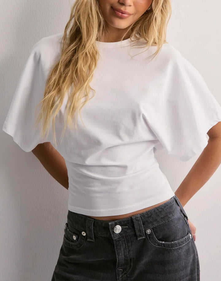 Female model walking pose wearing stylish fitted shirt plain background